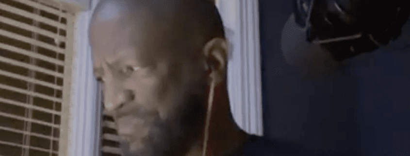 Man with earphones looking down, indoors.